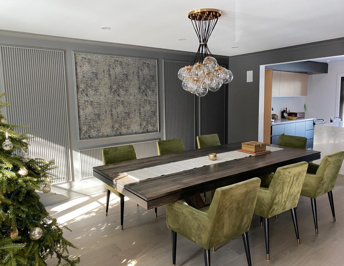 Modern dining room with green chairs, large wooden table, and a decorative chandelier.